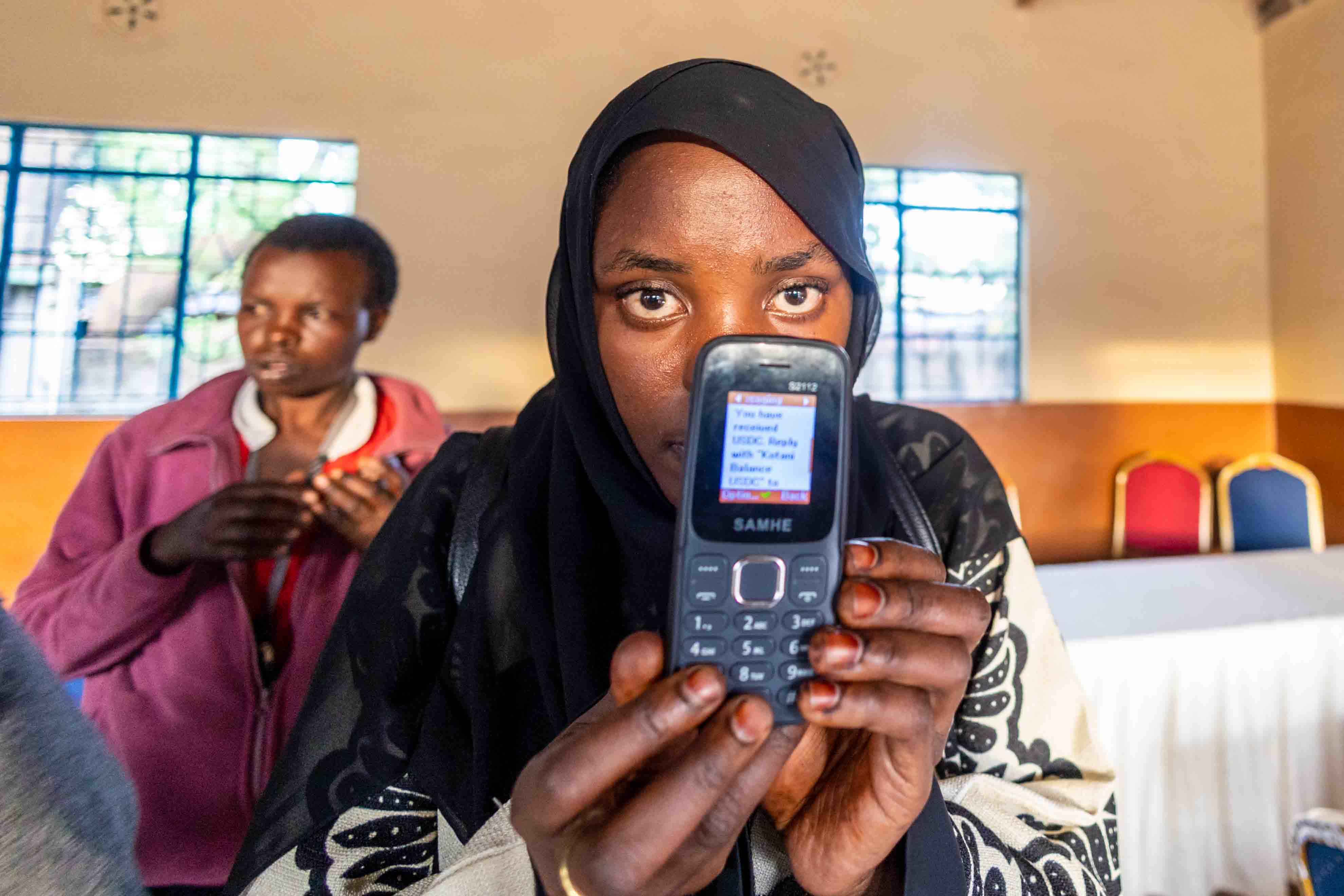 Begünstigte des AidLink-Pilotprojekts nutzt ein feature phone zum Empfang von Stablecoin-Transfers